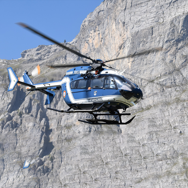 Blue helicopter in flight in front of mountain range