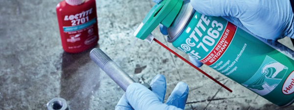 Loctite SF 7063 bottle next to metal screw. Loctite 2701 in the background